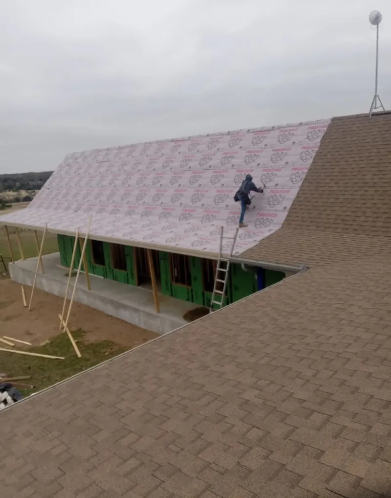 Worker preparing underlayment for a metal roof installation in Tewksbury